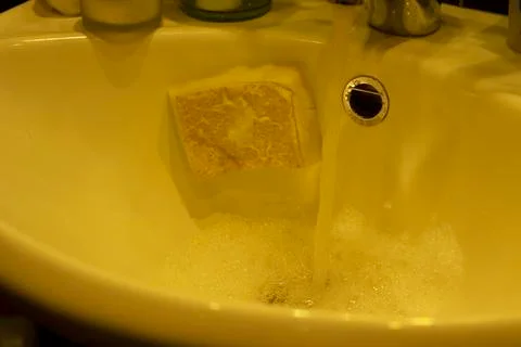 Actively using foam and sponge the child washes the washbasin in the bathroom Stock Photos