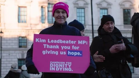 Activist supporting assisted dying bill smiles with placard Vidéo 293843701