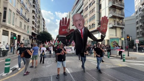 Activists carrying large Netanyahu protest puppet at Palestine march Stock Footage 336450628