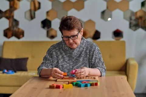 Activity can improve brain function. Elderly woman sitting at table and sorting Stock Photos