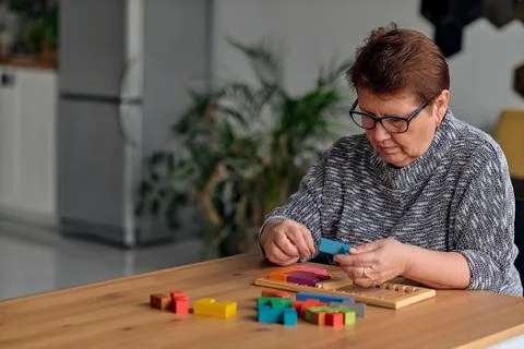 Activity can improve brain function. Elderly woman sitting at table and sorting Stock Photos