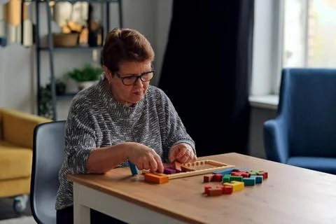 Activity can improve brain function. Elderly woman sitting at table and sorting Stock Photos