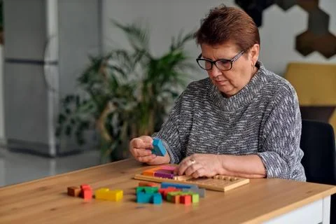 Activity can improve brain function. Elderly woman sitting at table and sorting Stock Photos