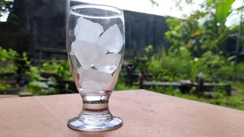 Activity Putting a Glass of Clear Ice Cube on a Wooden Table Stock Footage 304800734