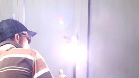 Activity of someone welding door hinges inside the house Stock Footage 238648639