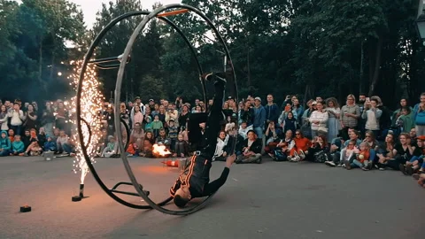 Actor of fire show performs trick with the wheel, rolling inside a metal wheel. Stock Footage 160804603