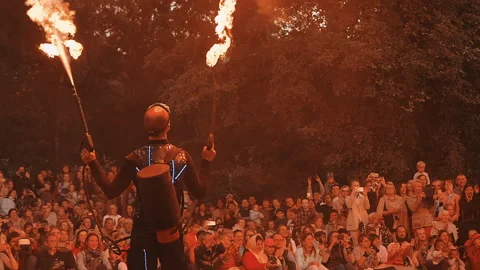 Actor of fire show shoots up from fire cannons, flames illuminate spectators. Stock Footage 160804300