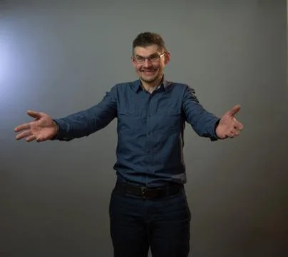 Actor in glasses smiles posing on stage with open arms Stock Photos