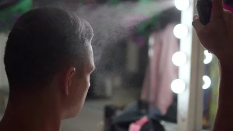 Actor man puts varnish spray on hair in front of mirror in dressing room - Stock Footage 150126054