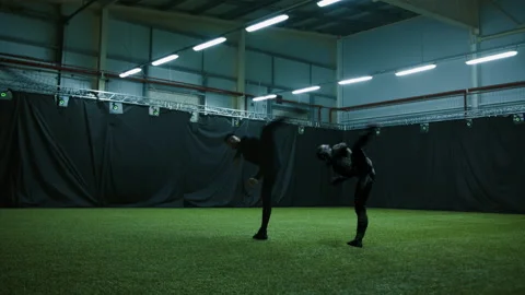 Actor in motion capture suit performing stunt moves next to a game character Stock Footage 172201154