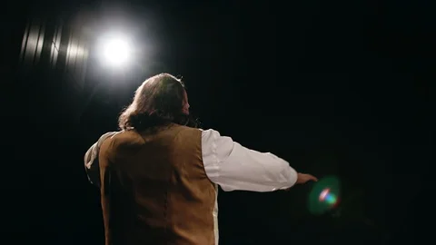 An actor plays a role on stage in front of a dark auditorium against the Stock Footage 129538988