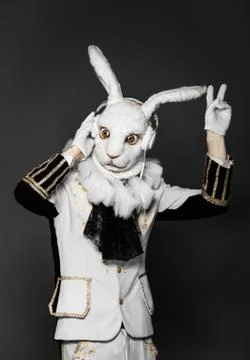 Actor posing in white rabbit suit with earphones on  black background.Studio Stock Photos
