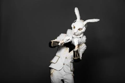 Actor posing in white rabbit suit with earphones on  black background.Studio Stock Photos