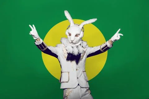Actor posing in white rabbit suit with earphones on color yellow green Stock-Fotos