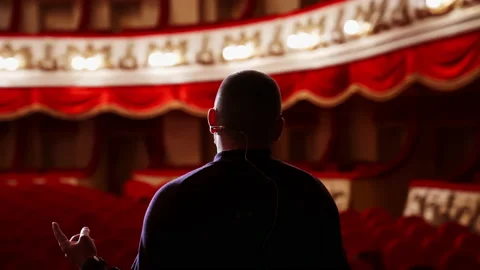 Actor rehearsing in front of empty auditorium. Back view of a man on stage again Stock Footage 149925091