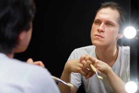 The actor sits in front of a mirror in a dark room Stock Photos
