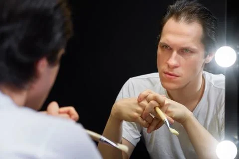 The actor sits in front of a mirror in a dark room Stock Photos