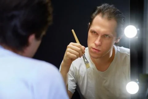 The actor sits in front of a mirror in a dark room Stock Photos