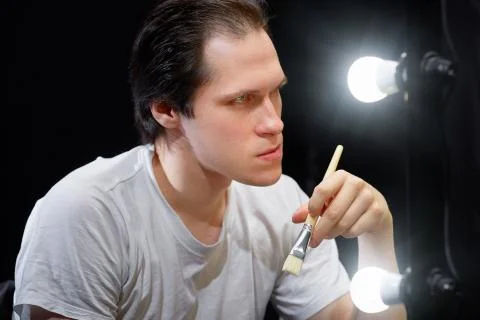 The actor sits in front of a mirror in a dark room Stock Photos