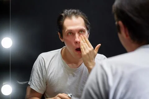 The actor sits in front of a mirror in a dark room Stock Photos