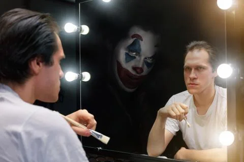 The actor sits in front of a mirror in a dark room Stock Photos
