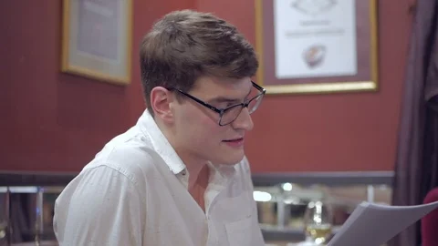 The actor, sitting in front of the audience in a cozy interior, reads prose from Stock Footage 103169077