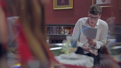 The actor, sitting in front of the audience in a cozy interior, reads prose from Stock Footage 103169096