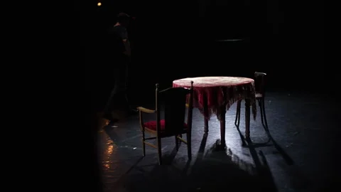 The actor walks across the stage next to an old table and chairs. Stock Footage 252496793