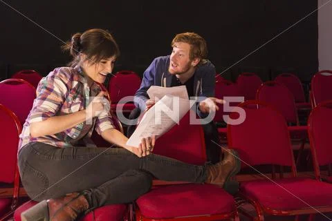 Actors Rehearsing In Red Theater Seats
