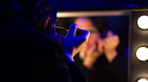 Actress applying makeup in front of the mirror in his dressing room. Stock Footage 61274786