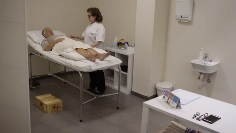 Acupuncturist manipulates needles inserted to a patient Stock Footage 99516097