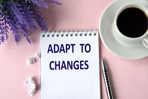 ADAPT TO CHANGES - words in a notebook on a pink background with a cup of cof Stock Photos