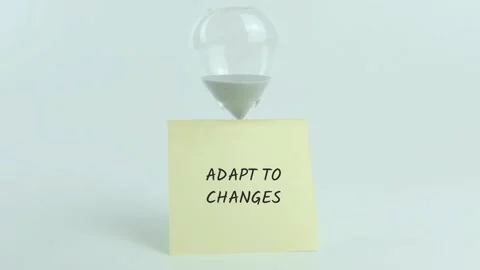 Adapt to Changes written on yellow sticky note placed on hourglass on white Stock Footage 313460456