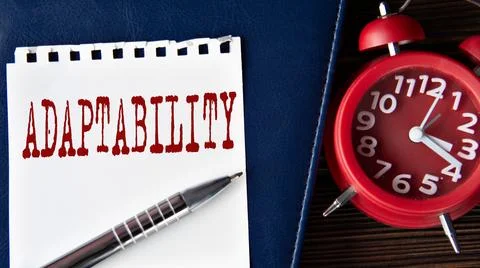 ADAPTABILITY - word on a white sheet on the background of a notebook, alarm.. Stock Photos