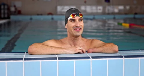 Adaptive amputee swimmer resting on side of indoor pool Stock Footage 146144066
