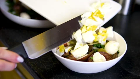 Add eggs to salad chef in the kitchen is slicing a boiled egg with a sharp knife 库存影片 302187048