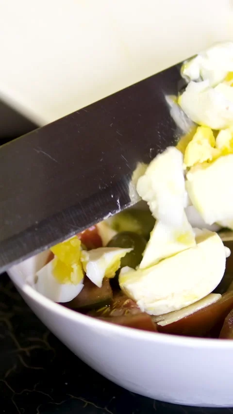 Add eggs to salad chef in the kitchen is slicing a boiled egg with a sharp knife 库存影片 302728757