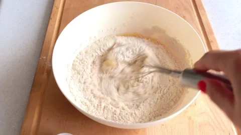 Add flour to the dough, sift and mix well in a white bowl Stock Footage 225042230
