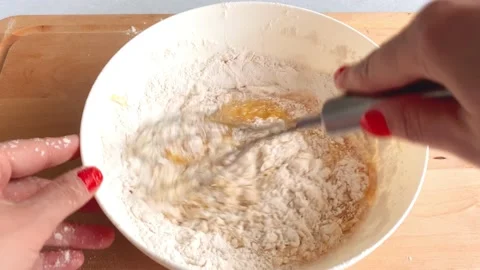 Add flour to the dough, sift and mix well in a white bowl Stock Footage 225044993