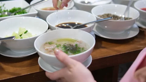 Add lime sprinkle with lime drops Vietnamese Pho bo Soup Close-up of hands Stock Footage 310158077