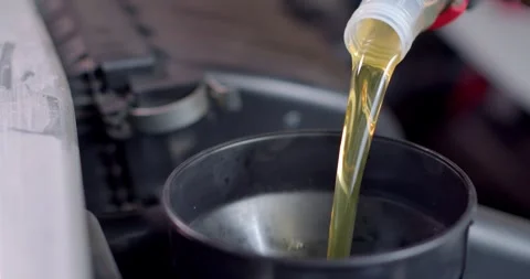 Add new engine oil to the engine. Extreme close up.New engine oil golden yellow. Stock Footage 277843296