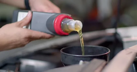 Add new engine oil to the engine.Close up engine oil. New golden yellow engine. Stock Footage 283484854