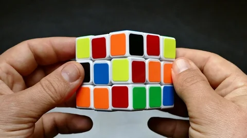 Add a Rubik's Cube. Pull the puzzle hands. Think over the solution of the Stock Footage 106087195