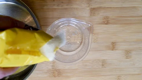 Add semolina in a measuring plastic Cup on the background of a wooden table Stock Footage 102754808