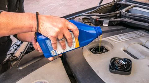 Added bottled engine oil directly into the engine compartment. mechanic adding Stock Photos