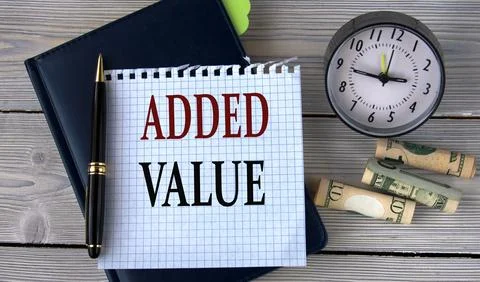 ADDED VALUE - words in a white notebook on the background of an alarm clock.. Stock Photos