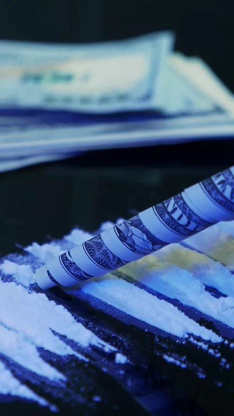 Addict sniffs line of cocaine through banknote from black table. Vertical video Stock Footage 335755691
