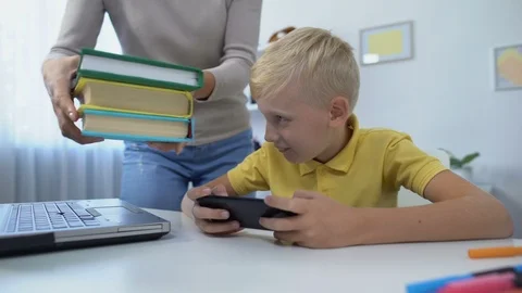 Addicted boy playing cellphone game instead of doing homework, mom scolding son Vídeos de archivo 118976184