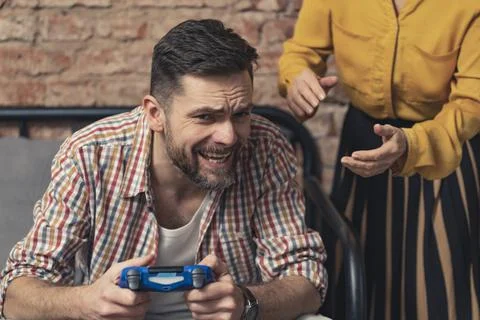Addicted caucasian man with a beard refuses to let go of the console pad and Stock Photos