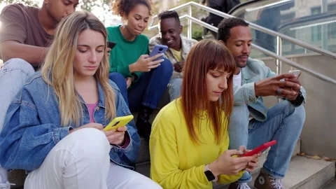 Addicted millennial young people using mobile phone sitting outside Vidéo 228831657